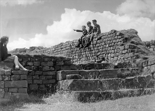 Schoolchildren sitting on the wall of the Roman Granary at Housesteads Fort in