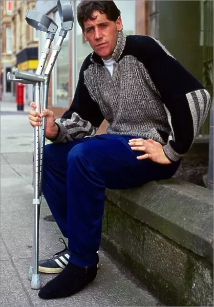 Ted McMinn sitting on wall with crutches September 1986