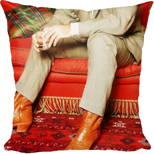Tom Jones singer sitting on red sette pale suit polo neck jumper glass boots tartan