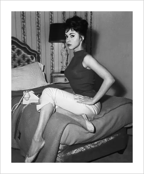 Actress Jackie Lane sitting on her bed with the phone March 1959