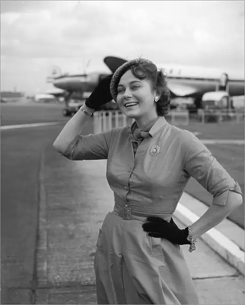 Actress Marta Torren holds on to her hat at the airport September 1956