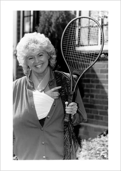 Gloria Hunniford TV Presenter holding the tennis racket she was useing when she broke her