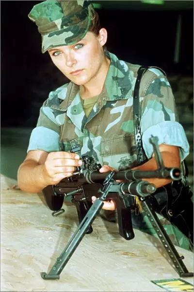 A woman soldier in the US army demonstrates a light machine gun at a daily press
