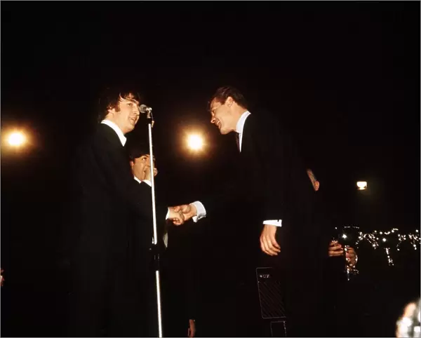 John Lennon and Paul McCartney of The Beatles receiving awards from Roger Moore at
