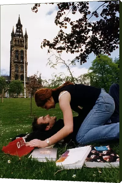 Students lay on the grass on campus kissing
