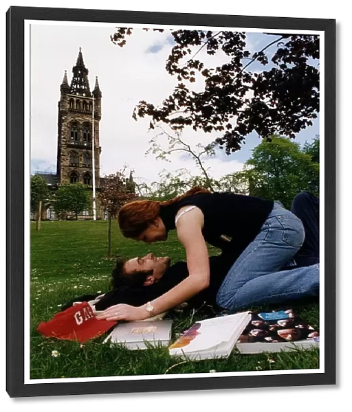 Students lay on the grass on campus kissing