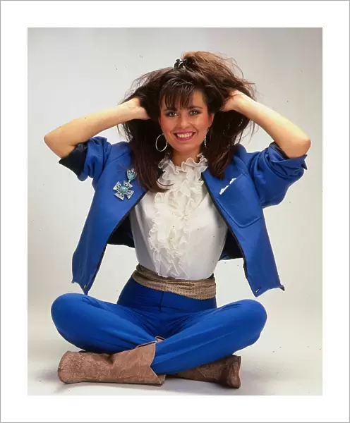 Debbie Greenwood TV presenter sitting on floor wearing blue jacket
