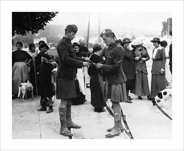 Curious French civilians watch two kilted Scottish soldiers. October 1914