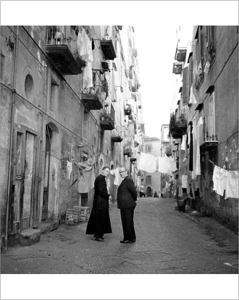 A priest chats to a elderly man in a street in the old town quarter of Naples in Southern