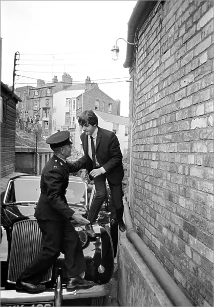 The Beatles August 1964 Paul McCartney is helped over his car by a guard to escape