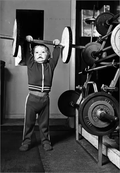 Two and half year old boy Ian Page lifts a set odf special wooden weights built for him