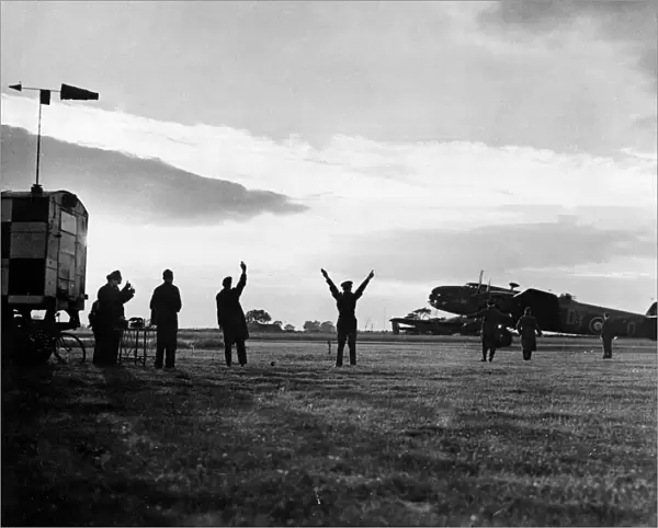 The group captain commanding officer of an RAF station signals a Halifax bomber to begin