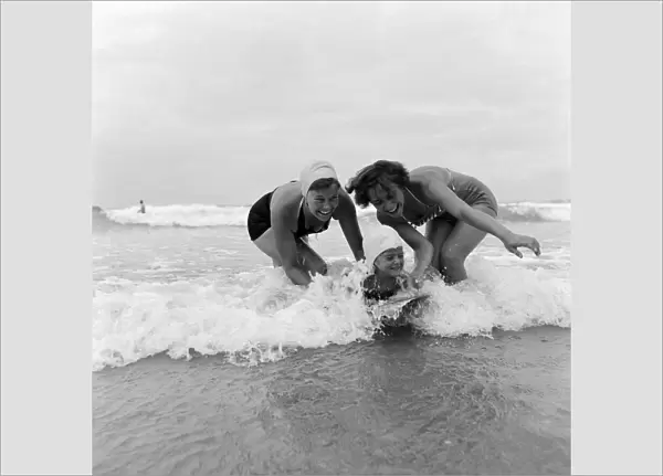 Two women and a child body boarding at Newquay, Cornwall, 23rd August 1953