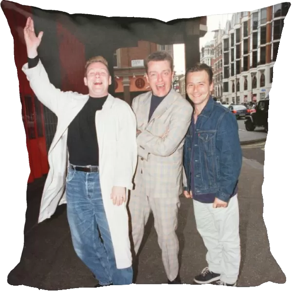 Suggs, lead singer of British ska group Madness, with two members of the group posing for