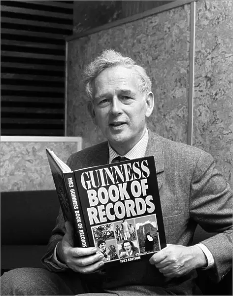 Norris McWhirter holding a copy of the Guinness Book of records