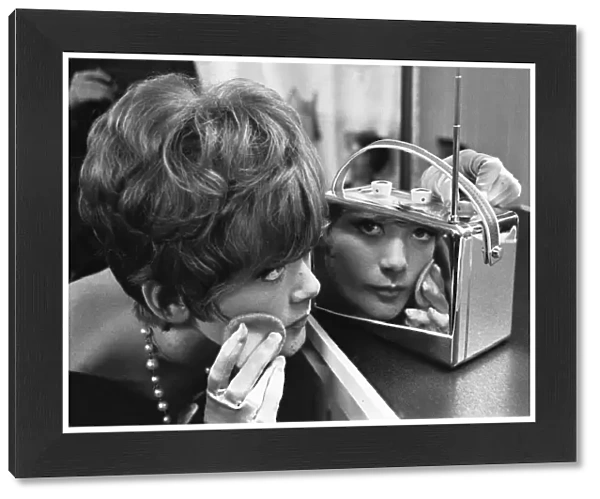 A young lady uses a chrome encased radio at the 1961 National Radio Show to touch up her