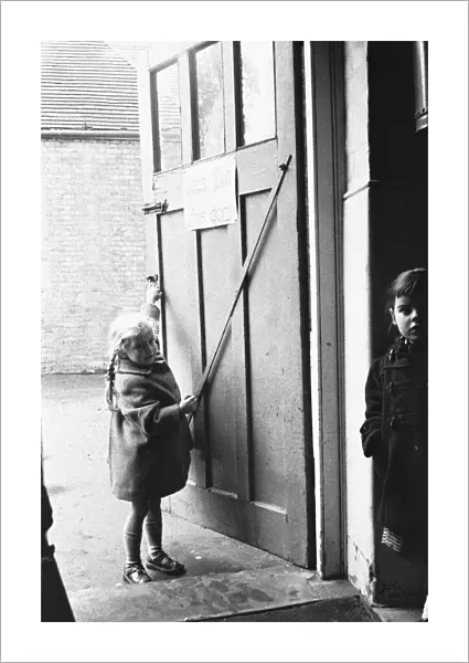 Child closing the door to the classroom following morning break at Roxeth Primary School