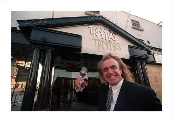 English nightclub owner Peter Stringfellow posing with a glass of champagne outside