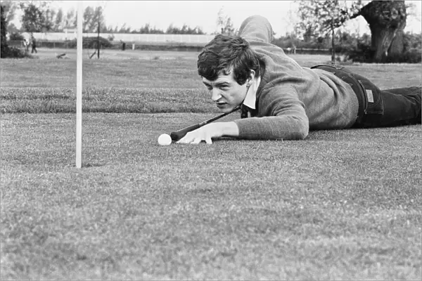 Snooker player Steve Davis on a golf course putting with a cue. 8th June 1981