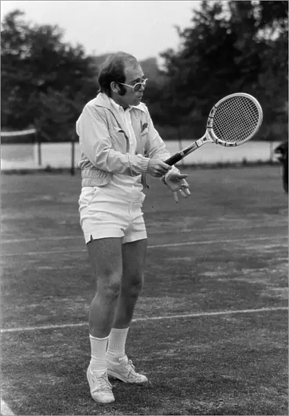 Elton John playing tennis on an outer court at Wimbledon. 25th June 1974