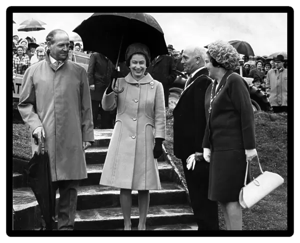 Queen Elizabeth II walks from the tree planting at Werneth Low carrying an umbrella to