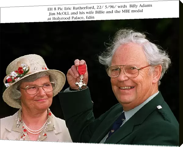 Jim McOll holding MBE medal at Holyrood Palace wife Billie looking
