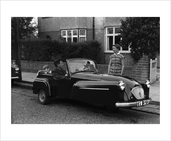 A father takes his son for a ride in his new convertible Bond mini car. Circa 1950
