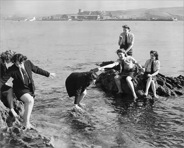 Service girls caught on the rocks in Plymouth, Devon. The US soldiers nearby