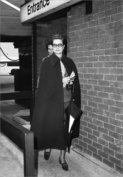 Princess Grace of Monaco, wearing a full length cape, as she arrives at Heathrow Airport