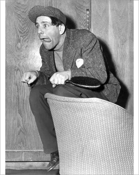 NORMAN WISDOM ACTS AS A JOCKEY ON HIS DRESSING ROOM SEAT, LONDON PALLADIUM - MAY 1954
