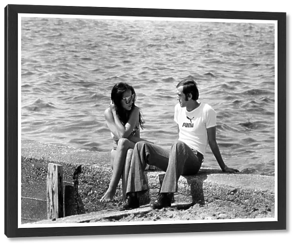 Couple sitting on a wall by he sea in Limassol, Cyprus May 1975