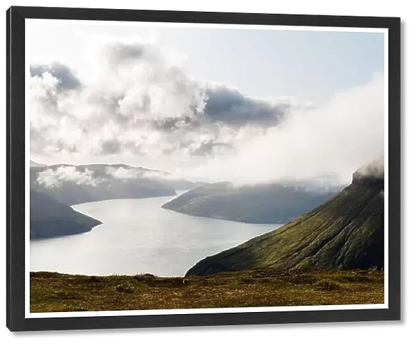 Foggy mountain peaks and clouds covering sea and mountains. Panoramical view from famous place - Sornfelli on Streymoy island, Faroe islands