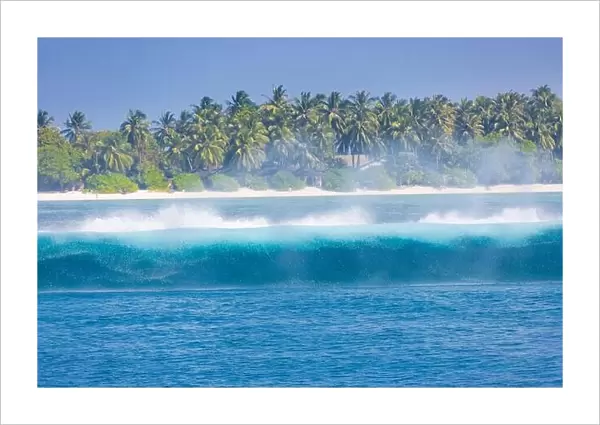 Tropical island with waves splashing. Tropical sea, palm trees and blue sky