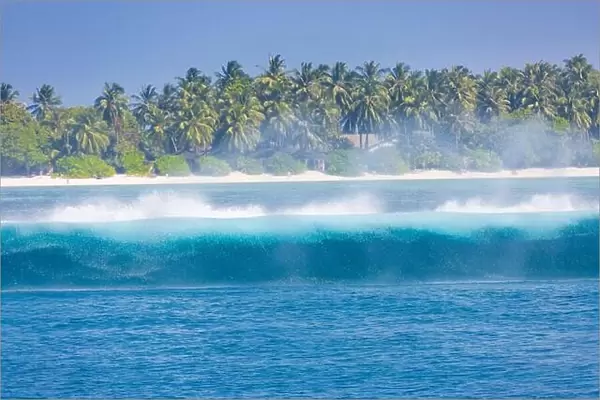 Tropical island with waves splashing. Tropical sea, palm trees and blue sky