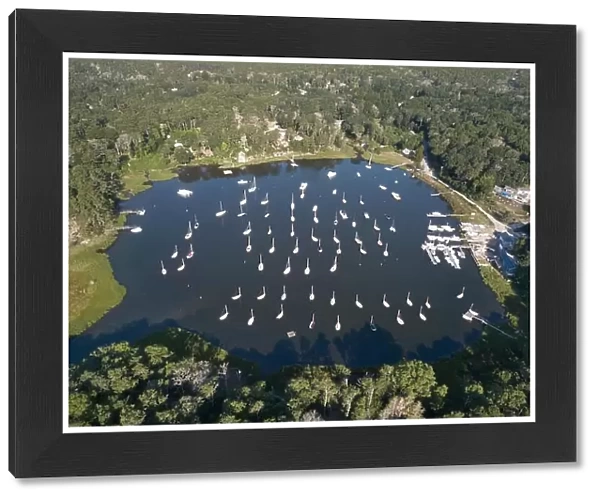 Dozens of sailboats are moored in a calm bay on Cape Cod, Massachusetts. This peninsula is a popular summer vacation destination in New England
