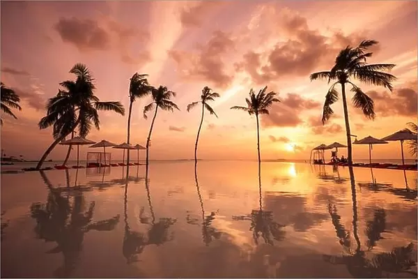 Luxury resort beach. Beautiful poolside and sunset sky. Luxurious tropical beach landscape, deck chairs and loungers infinity pool water reflection