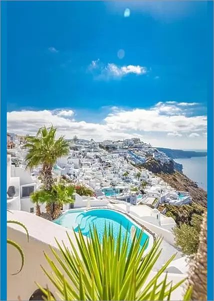 View of caldera and swimming pool in foreground, typical white architecture village on Santorini island, Greece. Summer vacations background. Luxury