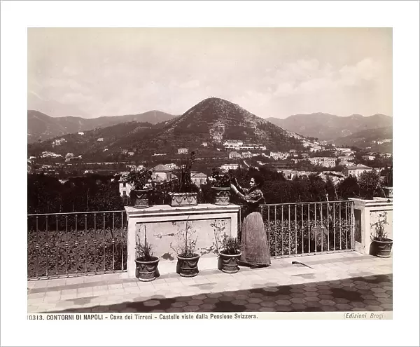 A woman arranges the plants on the terrace of the Svizzera Pension. In the background, Mount Castello in Cava dei Tirreni, near Naples
