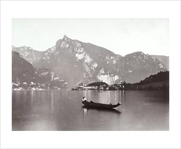 Man sitting on a boat, anchored in the centre of Lake Frauen, with the town of Frauenkirchen overlooking it, in Austria