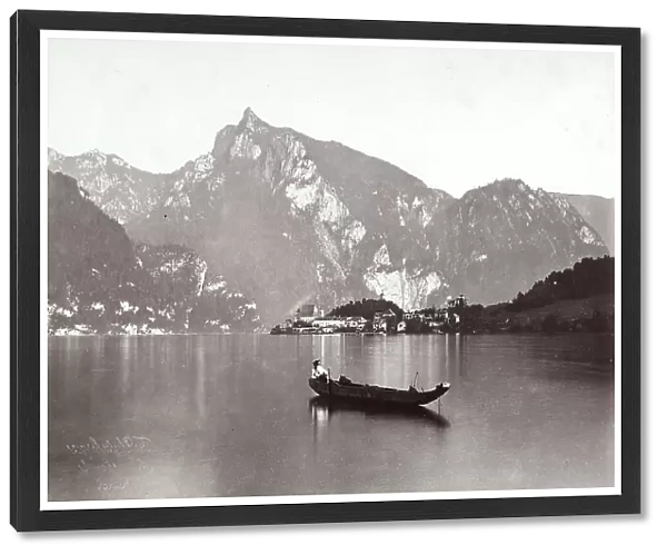 Man sitting on a boat, anchored in the centre of Lake Frauen, with the town of Frauenkirchen overlooking it, in Austria