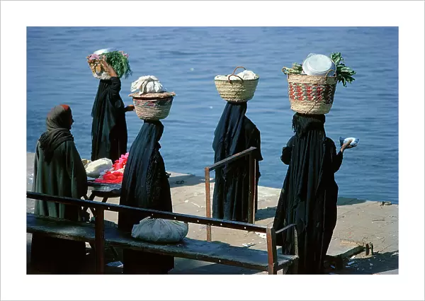 Luxor in Upper Egypt, women carrying baskets of vegetables to the market waiting to catch the ferry