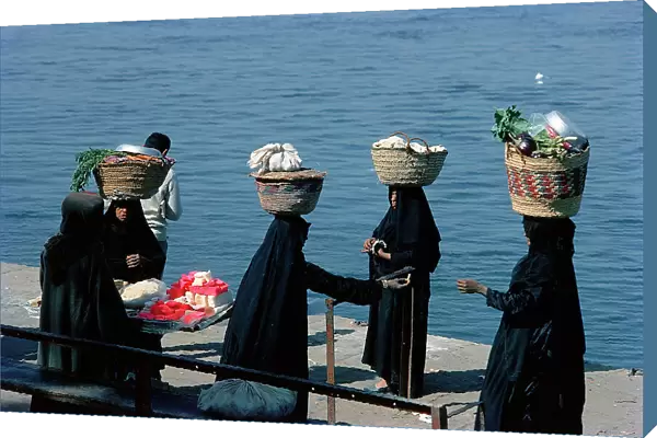 Luxor in Upper Egypt, women carrying baskets of vegetables to the market waiting to catch the ferry