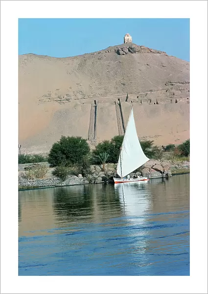 assuan a felucca passing along the coasts where there are some rich tombs of pharaonic lords of the court, on the top the tomb of a Muslim saint