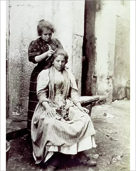 Young woman shown having her long hair dressed by a hairdresser