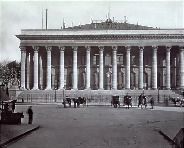 The classicizing building of the bourse in Paris, surrounded by tall columns on the square of the same name in front. A few carriages are waiting