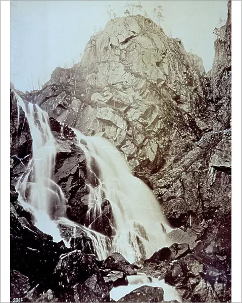 A waterfall that winds unevenly through a rocky landscape. It is probably in the vicinity of Bergen in Norway