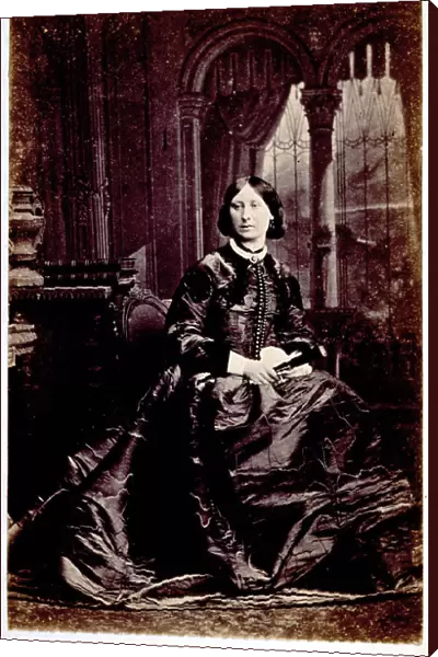 Full-length portrait of a young woman, seated. She wears luxurious daytime dress and holds a closed fan in her right hand