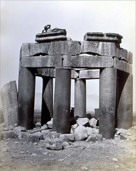 View of a funerary structure in Baalbek. It is octagonal in plan with eight large smooth columns, with an architrave and parts of the trabeation. At the top, lying down, a local boy. Around are ruins of the roofing