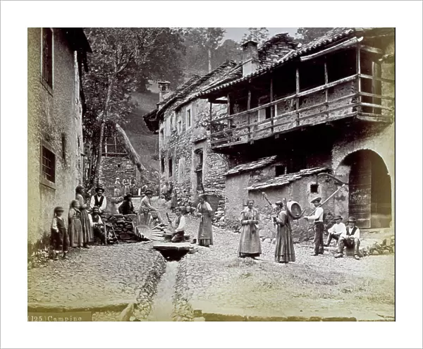A street in a small mountain hamlet. A few people, in traditional dress, are posing for the photographer