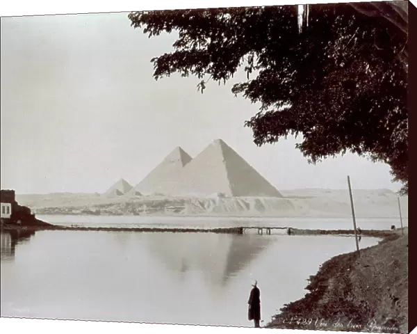 View of the three great pyramids of Khufu (Cheops), Khafre (Chefren) and Menkaure (Mycerinus) in the necropolis of Giza. In the foreground, a stretch of the Nile